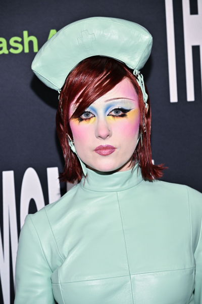 Chappell Roan appears at a premiere in a nurse's outfit. Her red hair is styled in a wetlook bob with a side bang.