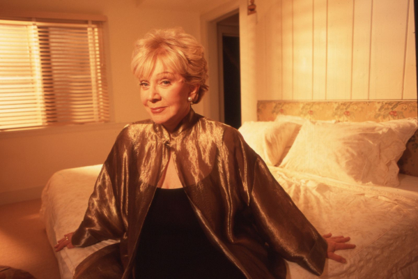 A photo of Joan Kron sitting on a bed